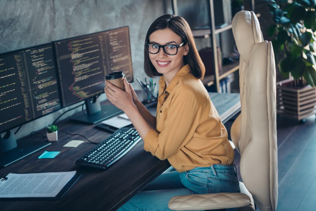 Smiling woman working remotely on a computer, representing flexible healthcare staffing solutions.