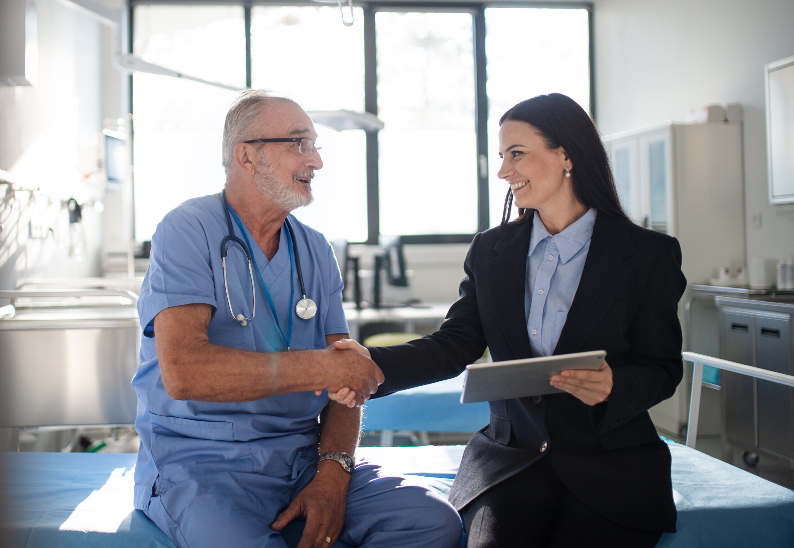 An older physician and female consultant discuss revenue cycle management (RCM) solutions for his healthcare organization.